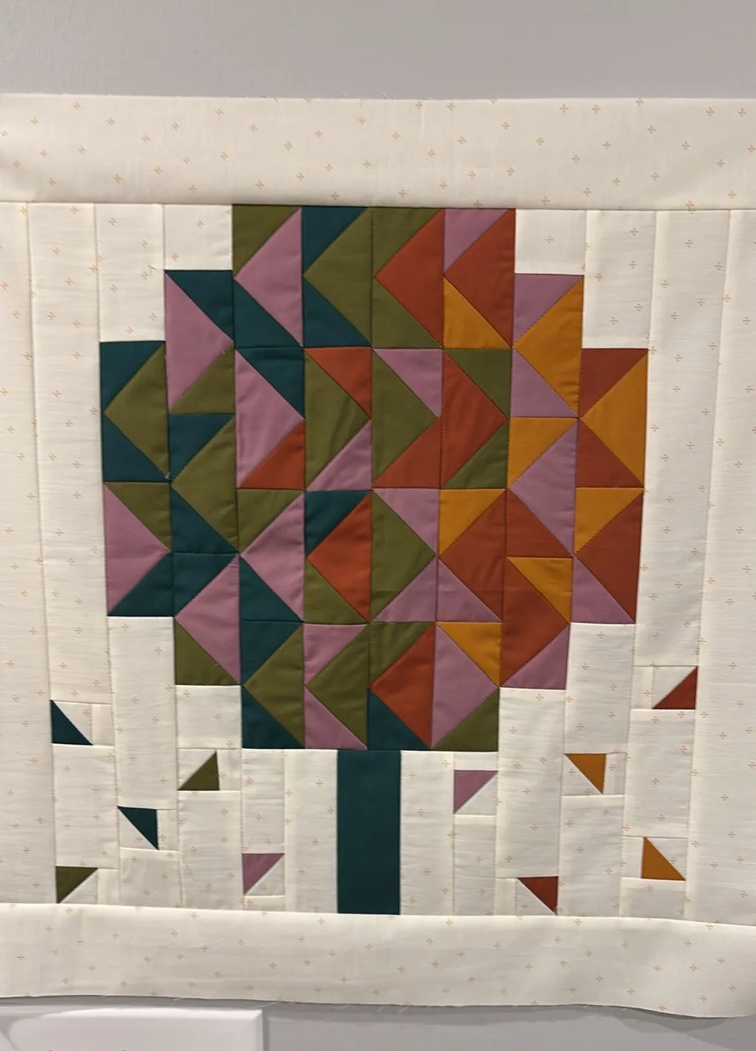 Quilted tree design with geometric leaf canopy in teal, olive, orange, and pink