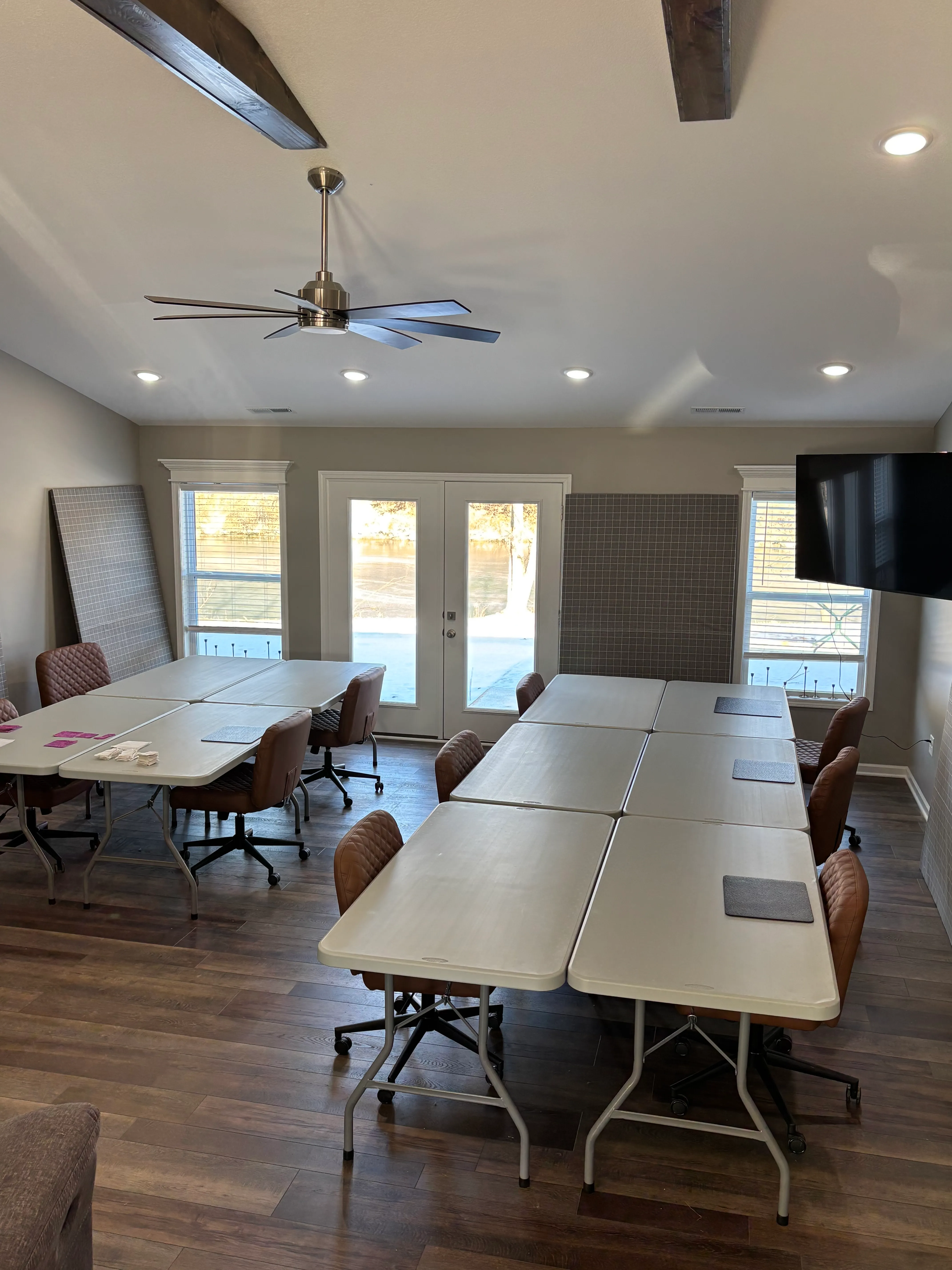 Quilting workspace with sewing machines, fabric bolts, and tools arranged on tables