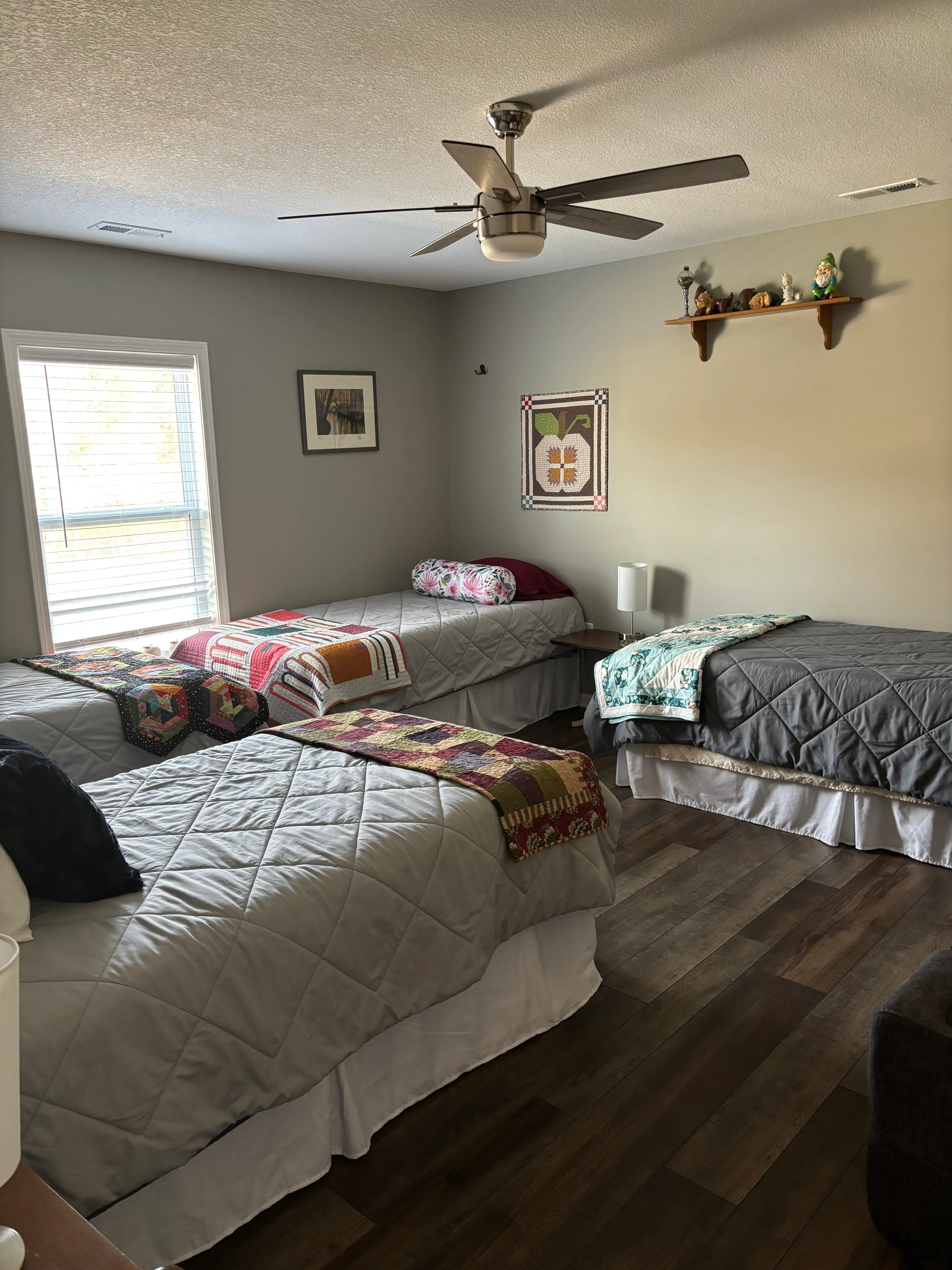 Bedroom with cozy beds and an array of quilted wall hangings in vibrant patterns
