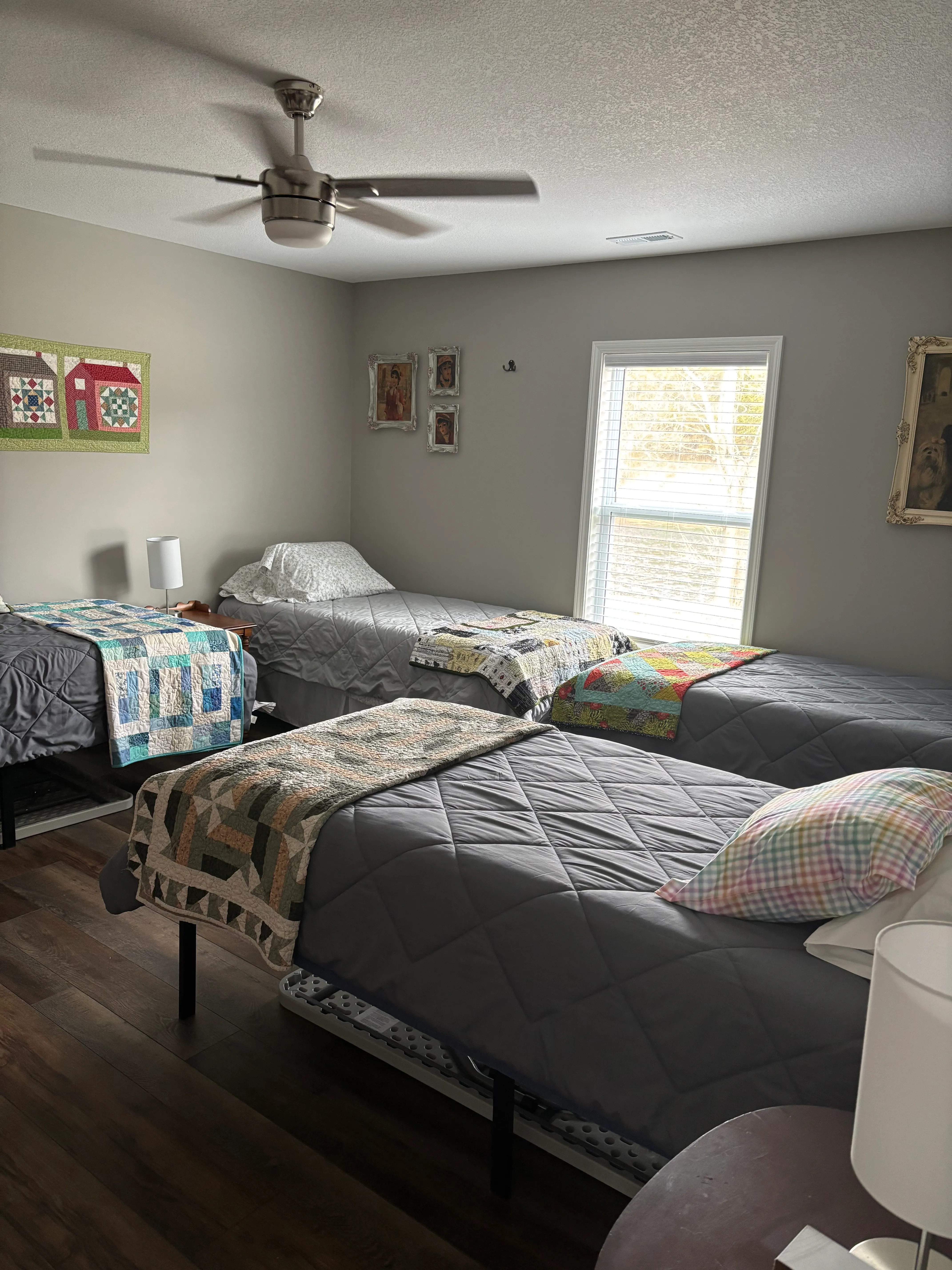 Bedroom with twin beds, quilted bedspreads, and a sunny window overlooking the property