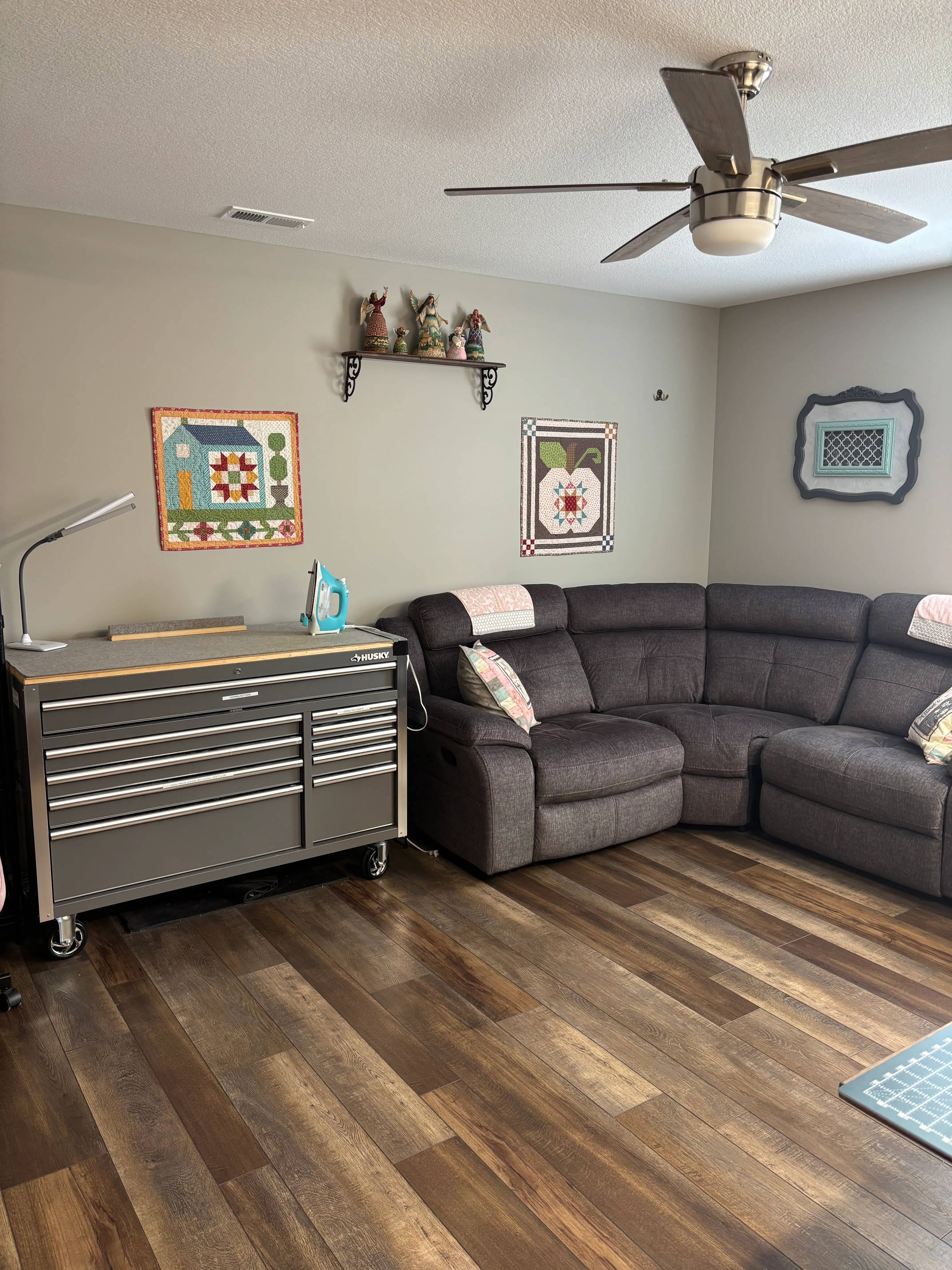Spacious common area with sectional sofa, handmade quilts on walls, and a vintage tool chest accent piece