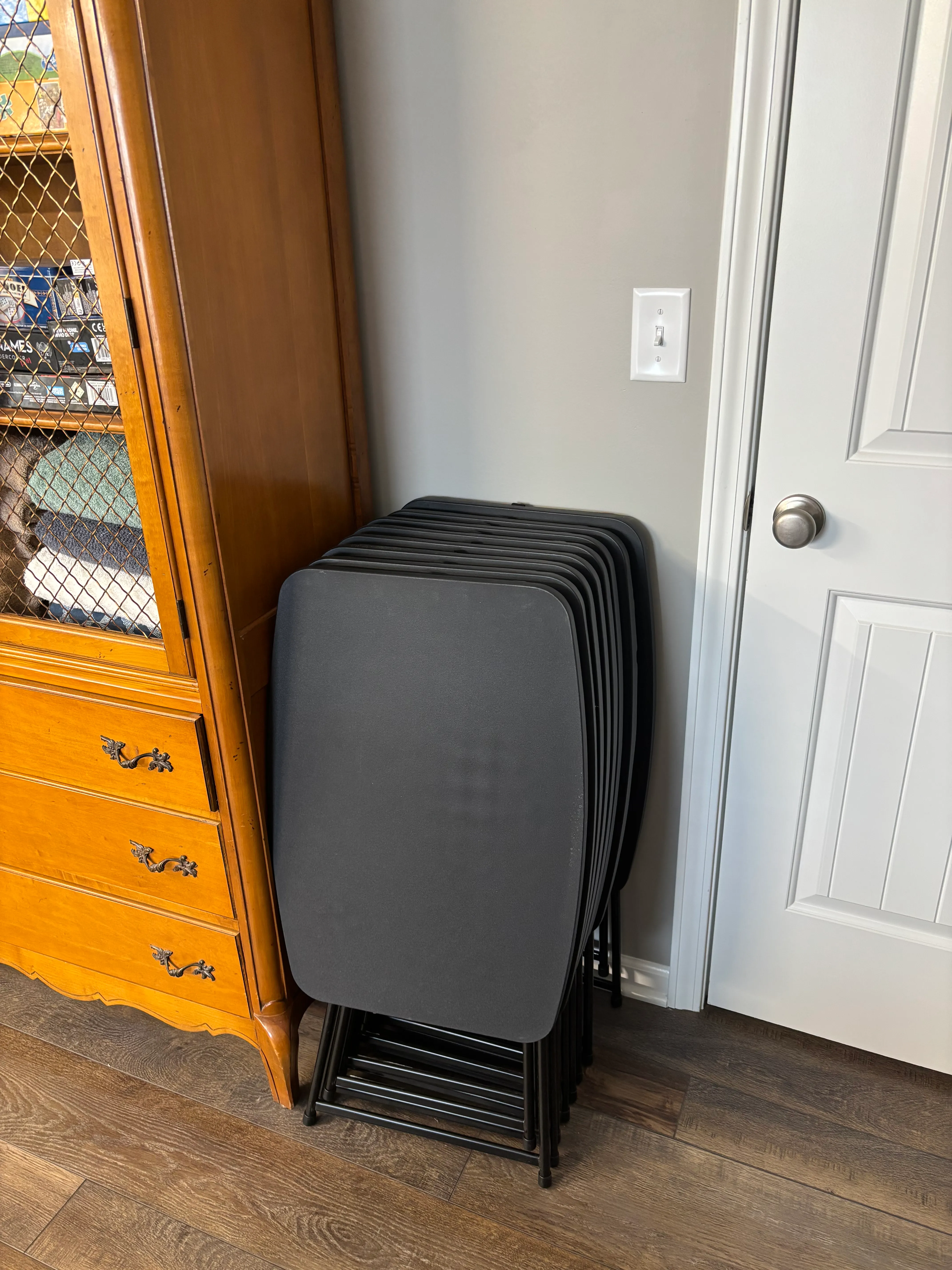 Stacked folding tables stored on a wooden cabinet, ready for additional workspace