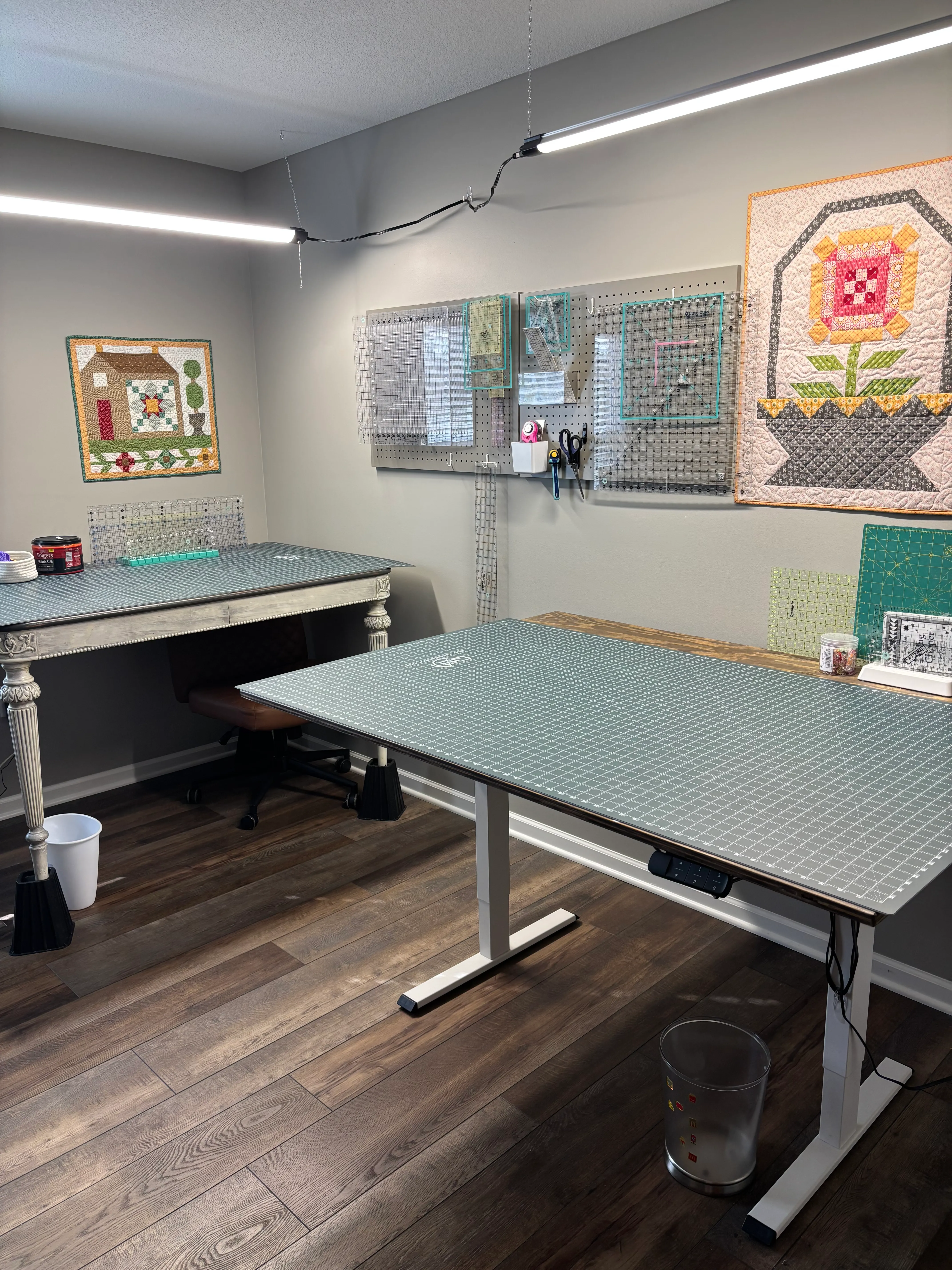 Quilting workspace with large cutting mat table and quilts on the wall